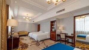 A hotel room with two beds, a desk, a chair, a lamp, and a large mirror.