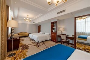 A hotel room with two beds, a desk, a chair, a lamp, and a large mirror.