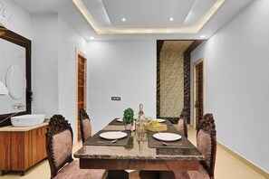 Un comedor con una mesa rectangular dispuesta para cuatro personas, rodeada de sillas tapizadas.