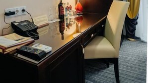 A hotel room with a flat-screen TV mounted on the wall, a desk with a lamp, a chair, and a bed. - Optima Collection Chernihiv (Chernihiv)
