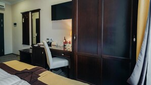 A hotel room with a bed, a desk, a chair, a wardrobe, a television, and a minibar. - Optima Collection Chernihiv (Chernihiv)