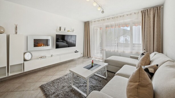 A modern living room with a flat-screen TV, a fireplace, a sofa, and a coffee table.