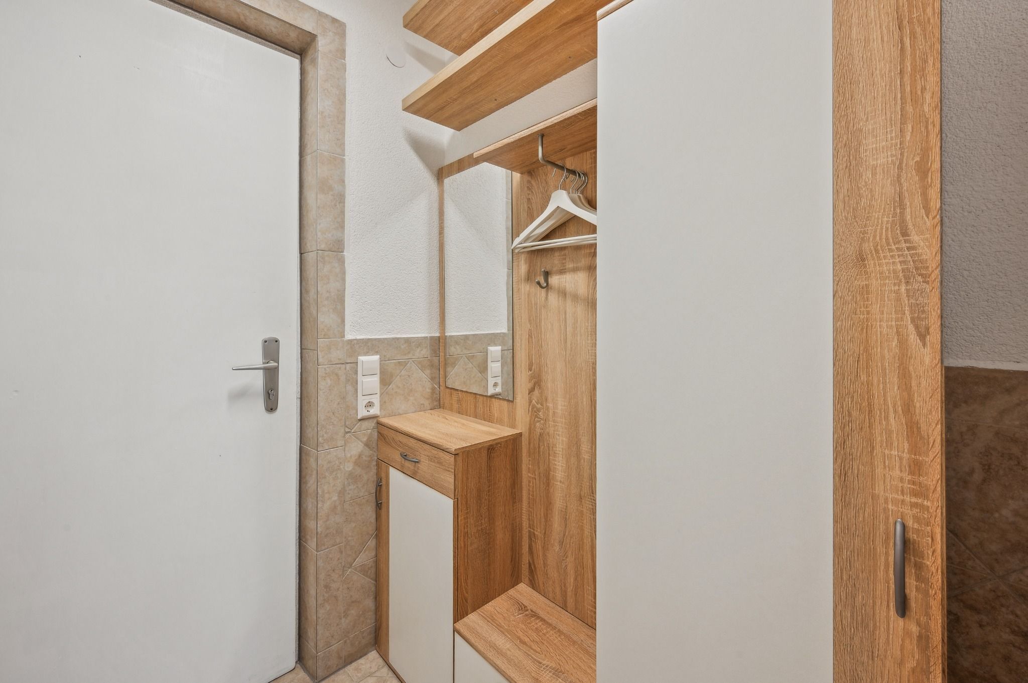 Een badkamer met een houten wastafelmeubel, een handdoekhouder en een spiegel.