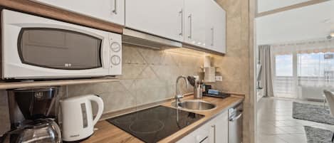 A modern kitchen with a microwave, coffee maker, and induction cooktop.