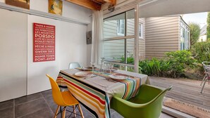 A dining area with a table set for two, chairs, and a view of the outside.