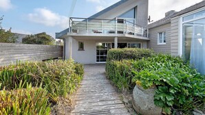 A modern house with a balcony, a wooden pathway, and a garden.