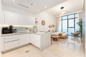 Una cocina moderna con armarios blancos, una isla central y un comedor con sofá y sillón.