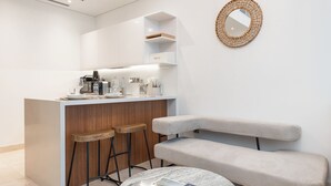 Una cocina moderna con barra, taburetes, un banco y una mesa redonda con una revista.