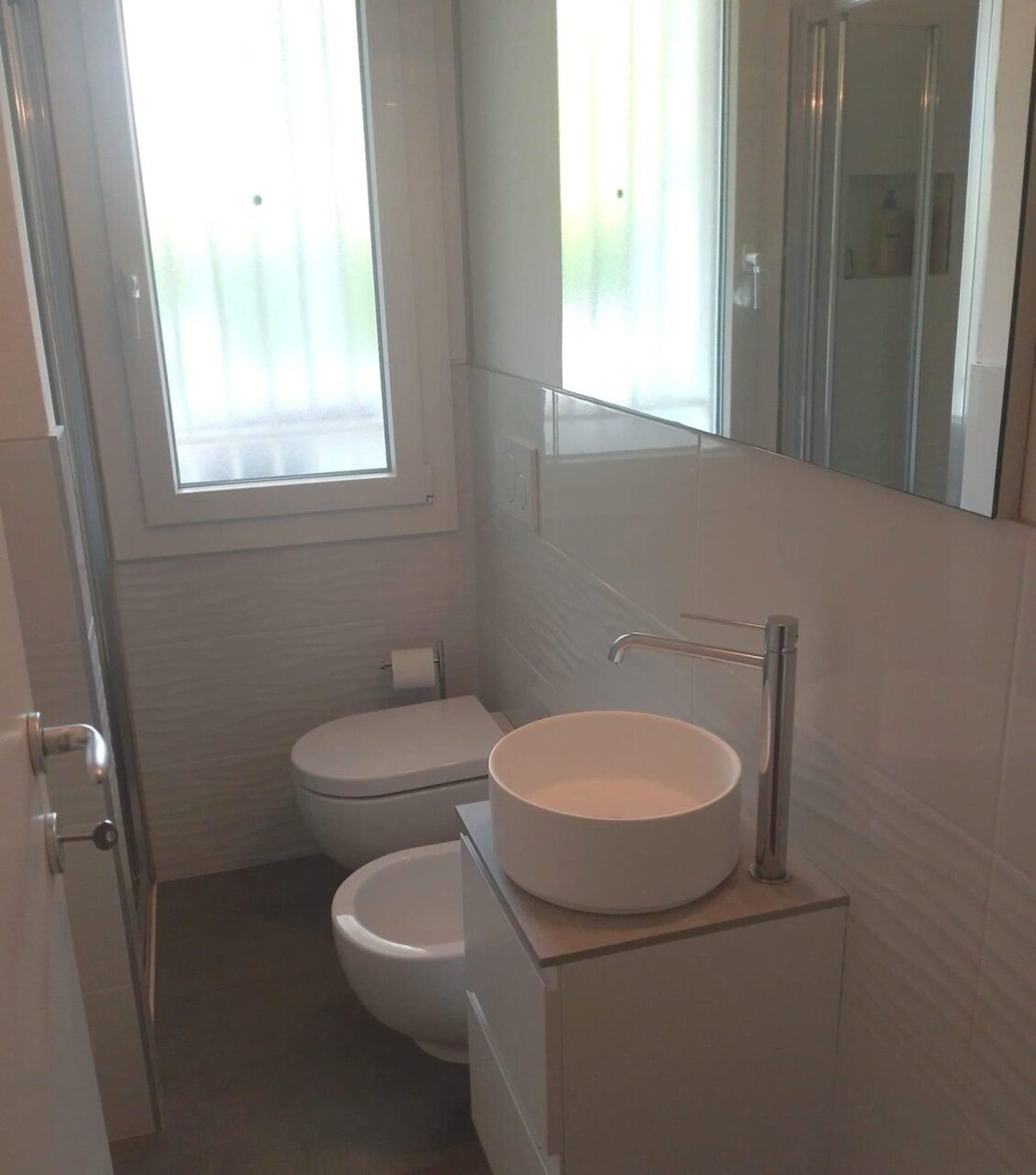 A small, modern bathroom with a toilet, a sink, and a mirror.