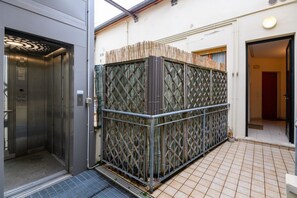 Un ascensore, un cancello metallico e un pavimento piastrellato.