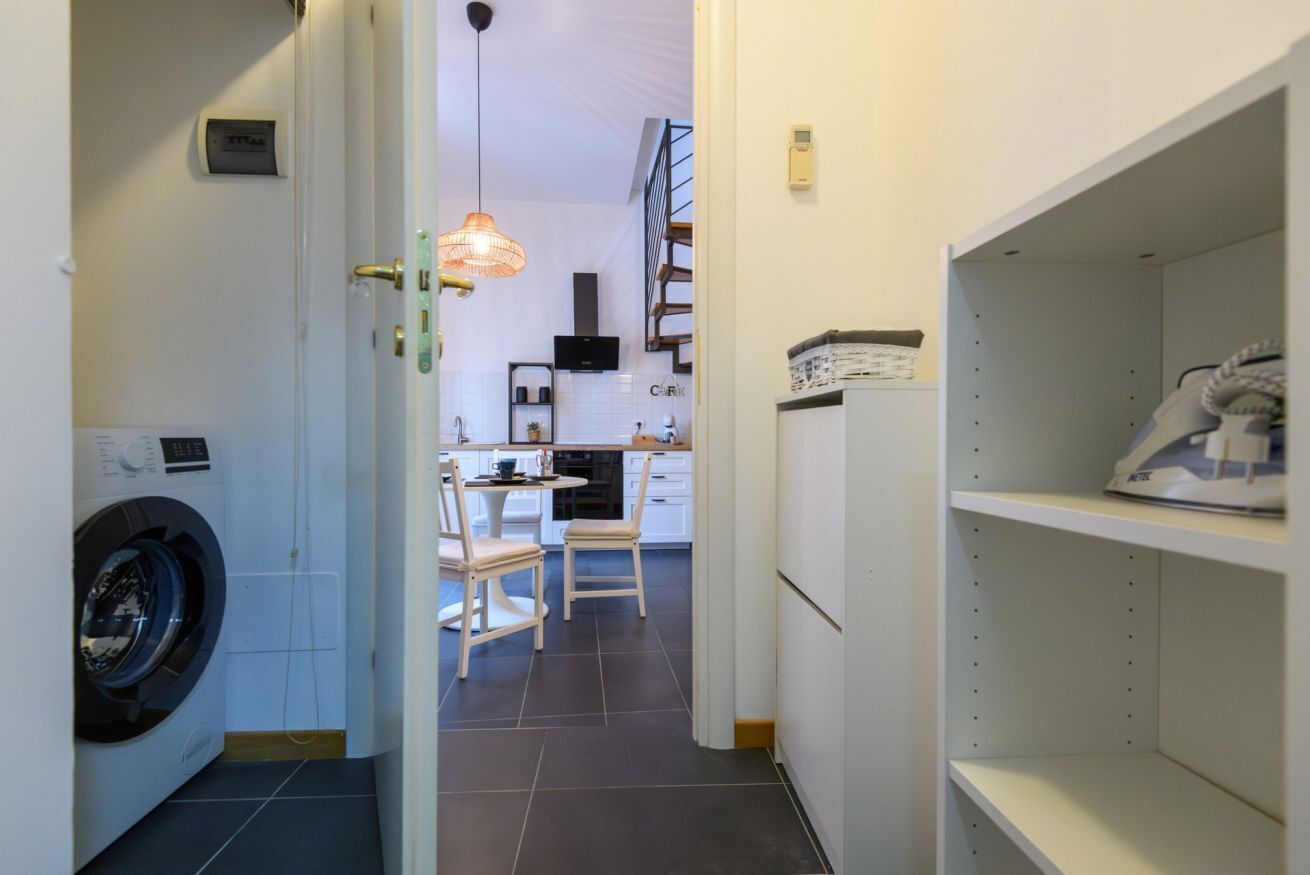 Un espace buanderie avec un lave-linge, une table à manger avec des chaises, et une cuisine en arrière-plan.