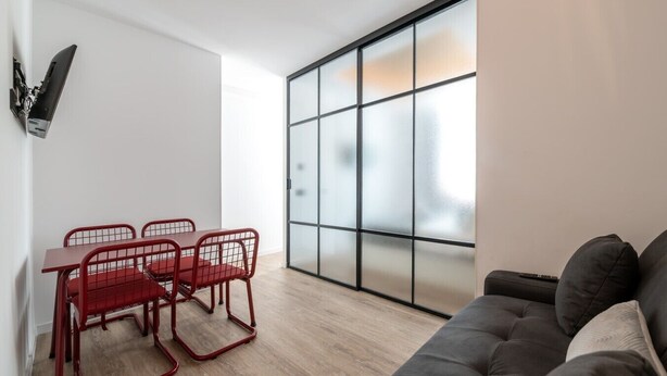 Un salon moderne comprenant un canapé, une table à manger avec des chaises et une grande fenêtre dot ée de panneaux en verre dépoli.