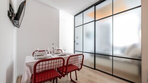 Un coin repas avec une table dressée pour deux personnes, des chaises au design moderne et une grande fenêtre dotée de panneaux en verre dépoli.