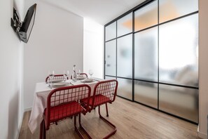 A dining area with a table set for two, a modern chair design, and a large window with frosted glass panels. - 505 - A33 Signature | Penthouse | Terr | 2BR | 6G (Madrid)