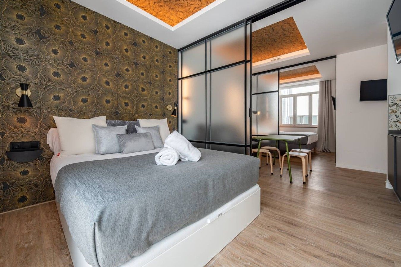 A modern bedroom with a large bed, a desk, and a dining area.