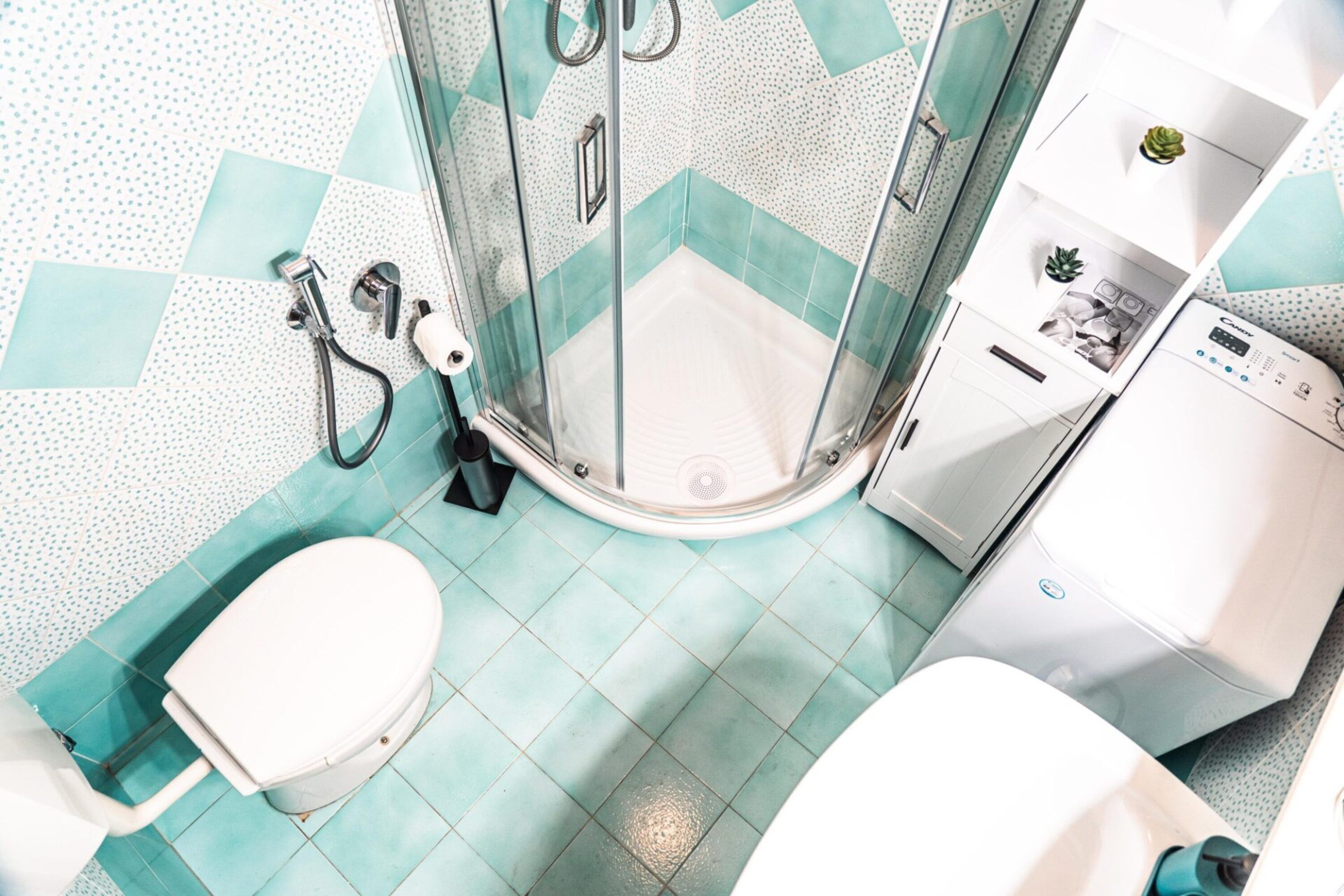 A bathroom with a shower, toilet, and a washing machine.