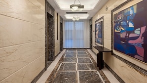 A hallway with marble walls, a patterned floor, a ceiling light, and artwork on the walls. - Days Inn by Wyndham Nanchang Donghu (Nanchang)