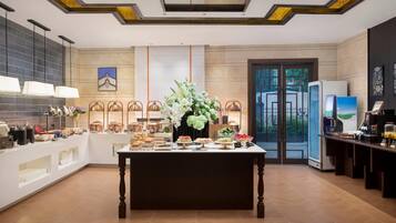 A hotel lobby with a reception desk, a coffee station, and a buffet area.
