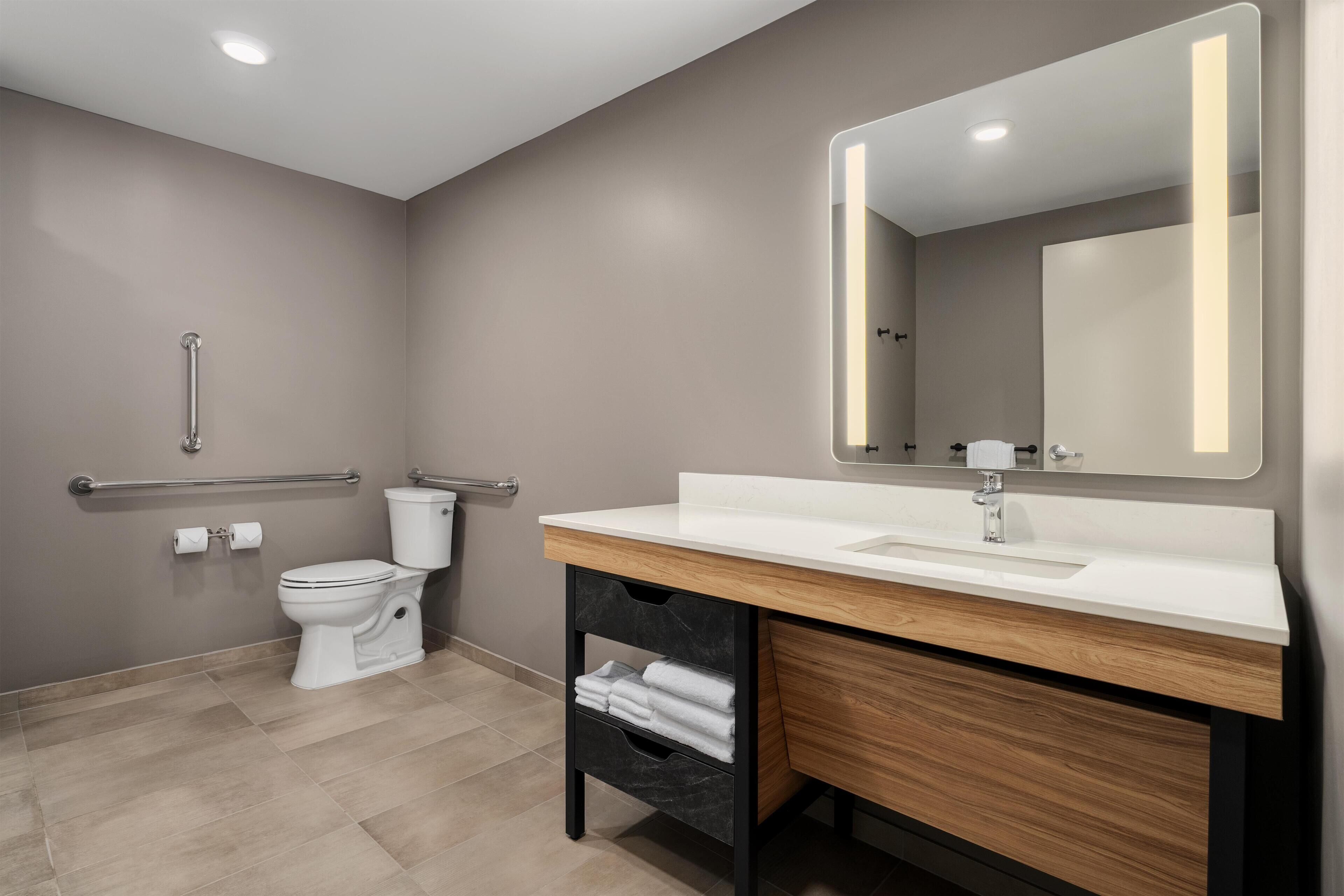 Une salle de bain moderne avec des toilettes, un lavabo et un miroir.