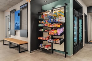 Un petit kiosque où l’on vend divers produits emballés, avec un banc à proximité.