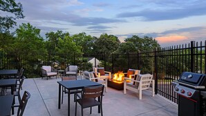 Una terrazza esterna con un braciere, posti a sedere e un barbecue.