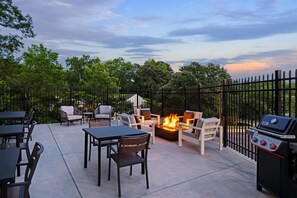 Une terrasse extérieure avec un foyer, des sièges et un barbecue.