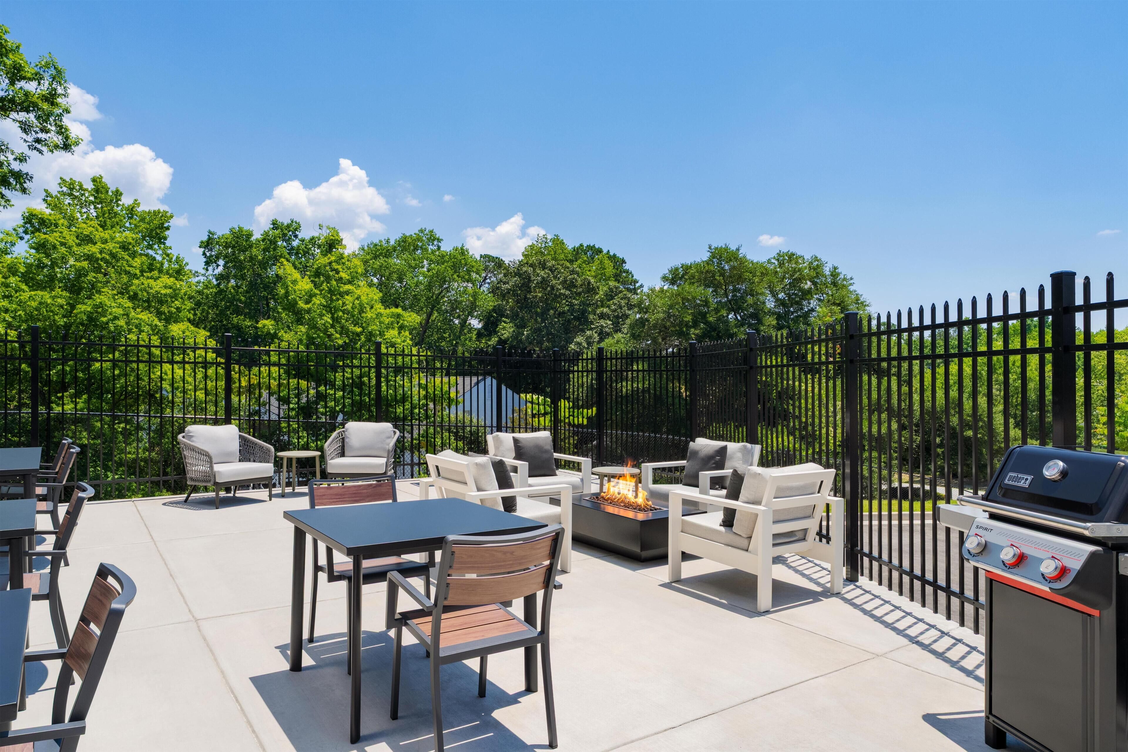 Une terrasse extérieure équipée d’un barbecue, de sièges et d’un foyer.