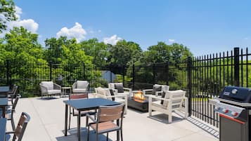 Une terrasse extérieure équipée d’un barbecue, de sièges et d’un foyer.