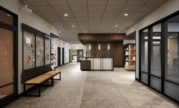 Un intérieur moderne comprenant un comptoir d’accueil, un banc et un mur sur lequel est fixé un tableau d’affichage.