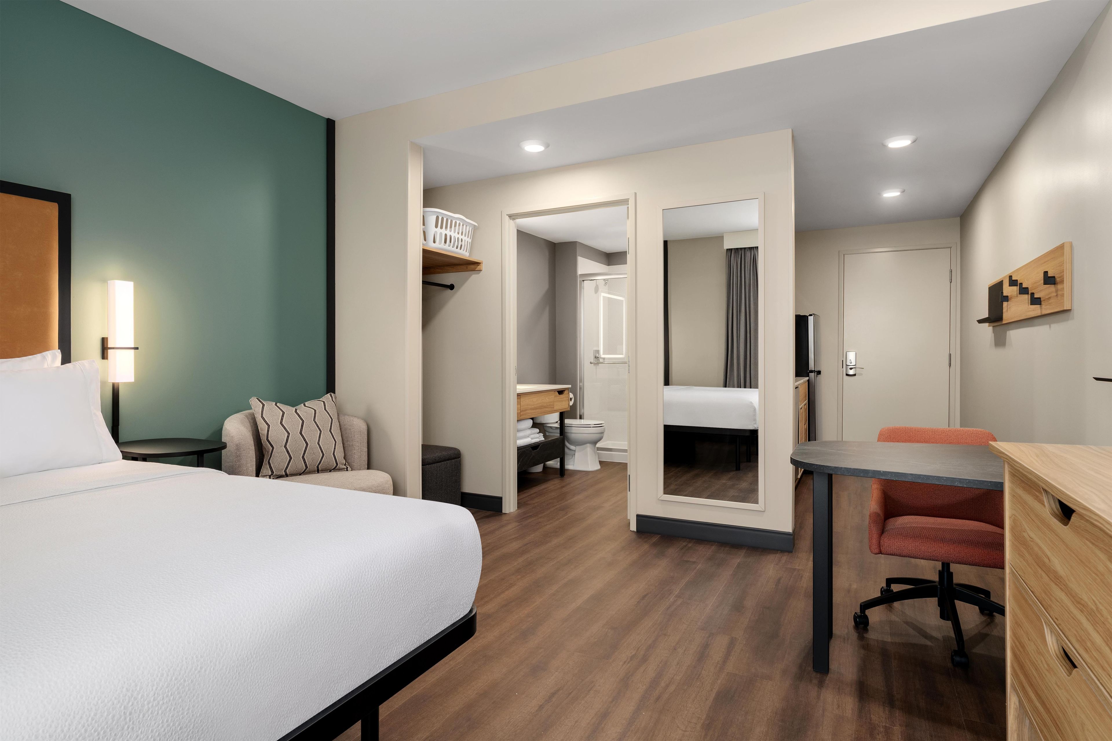 Ein Hotelzimmer mit Bett, Schreibtisch, Stuhl, Badezimmer und Kleiderschrank.