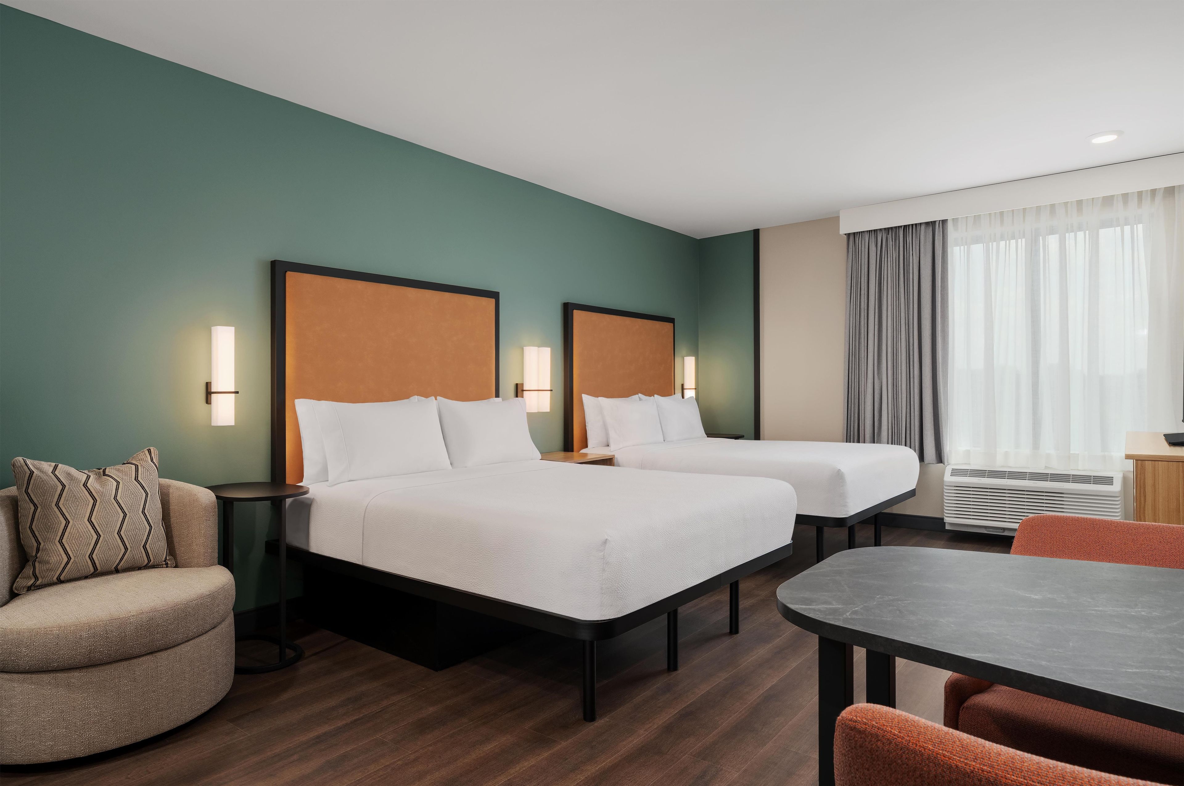 Une chambre d’hôtel avec deux lits, un bureau, une chaise et un canapé.