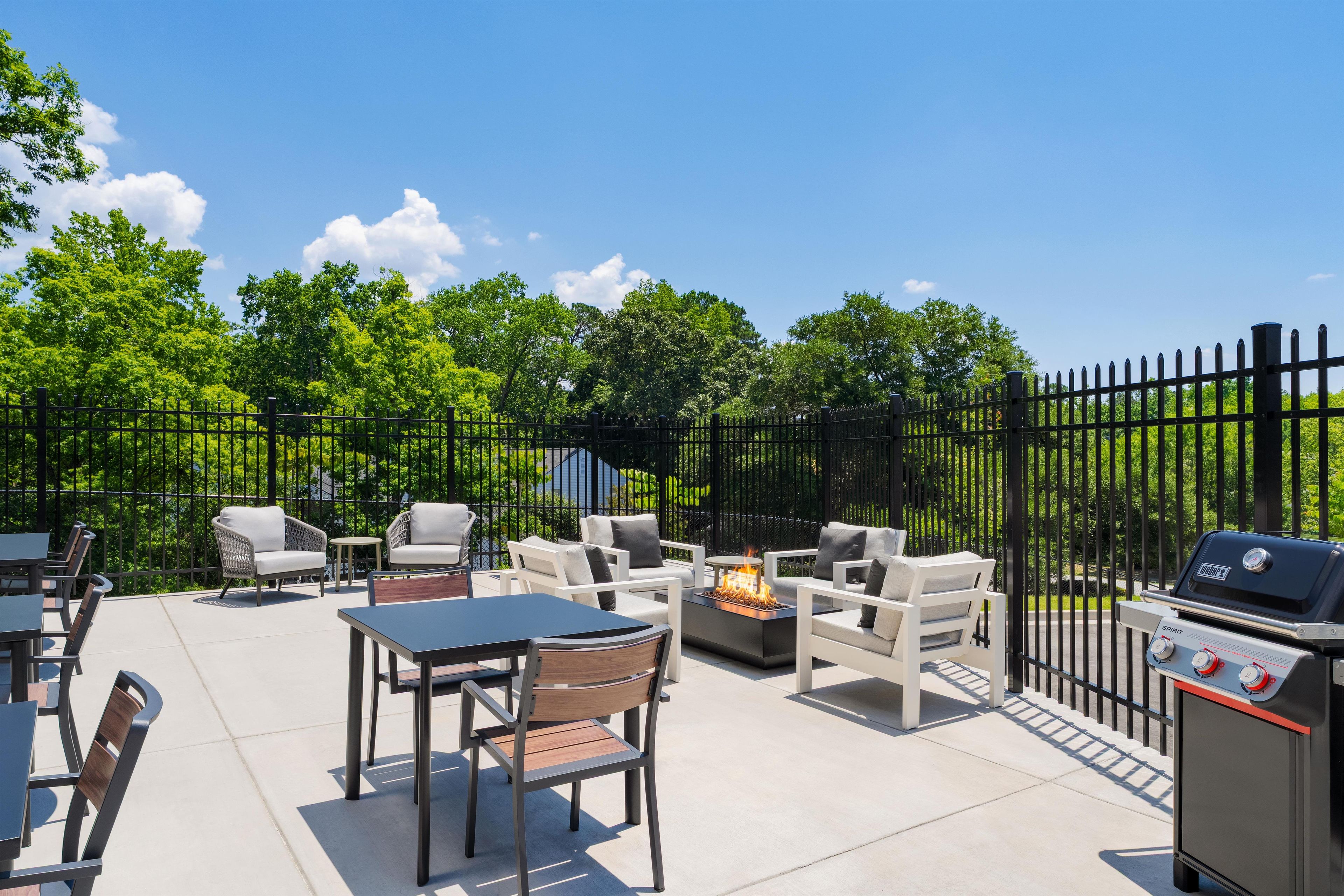 An outdoor patio with a grill, seating, and a fire feature.