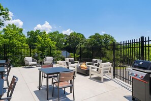 An outdoor patio with a grill, seating, and a fire feature. - LivSmart Studios by Hilton Columbia Greystone (Columbia)