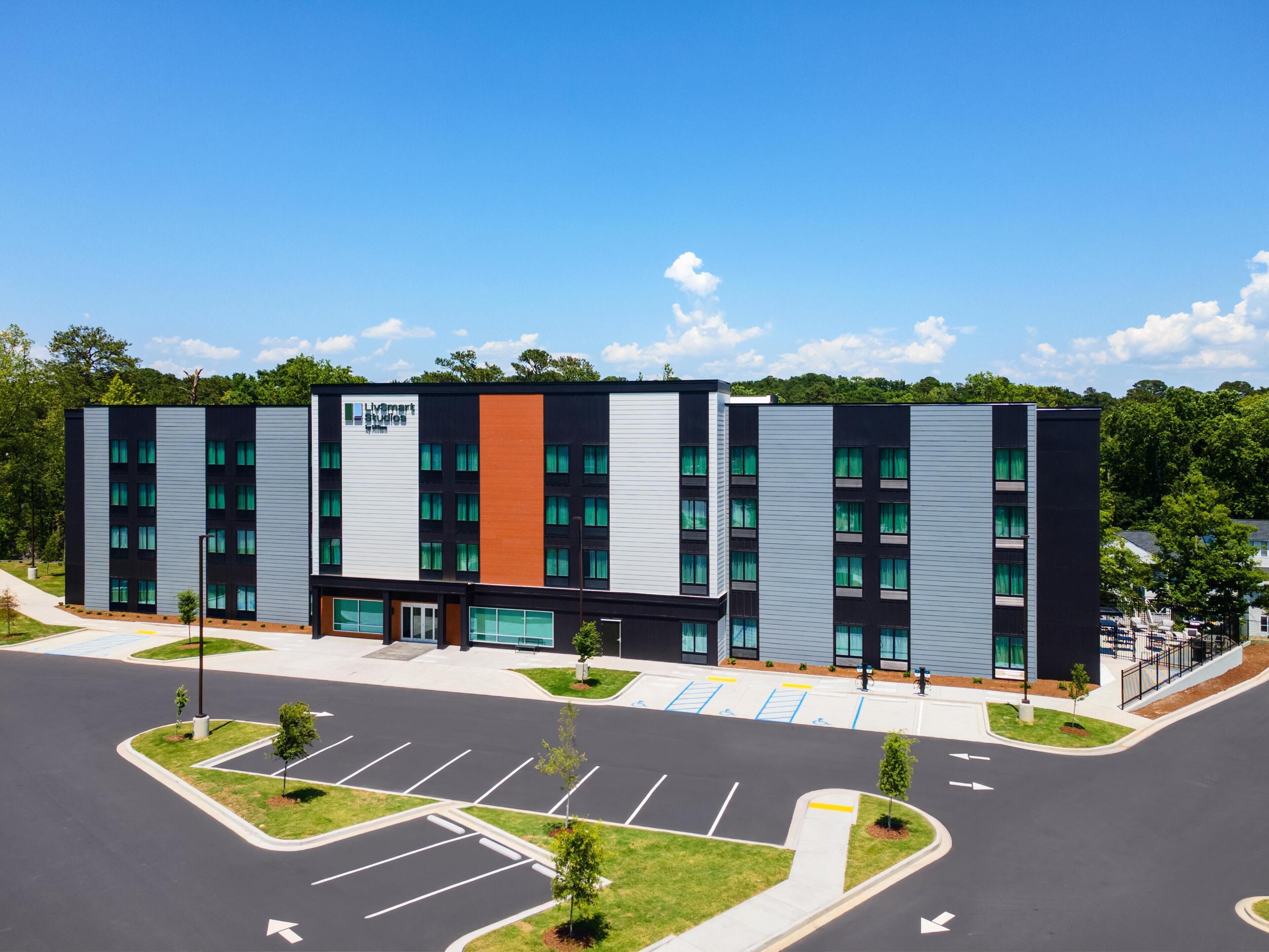 A modern building with a flat roof, multiple windows, and a parking lot with marked spaces.