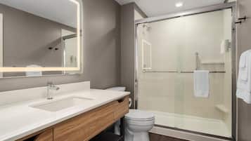 A modern bathroom with a glass-enclosed shower, a white sink, and a vanity with a mirror.