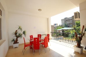 A balcony with a dining table and chairs, potted plants, and a view of buildings. - Family Hotel (Yerevan)