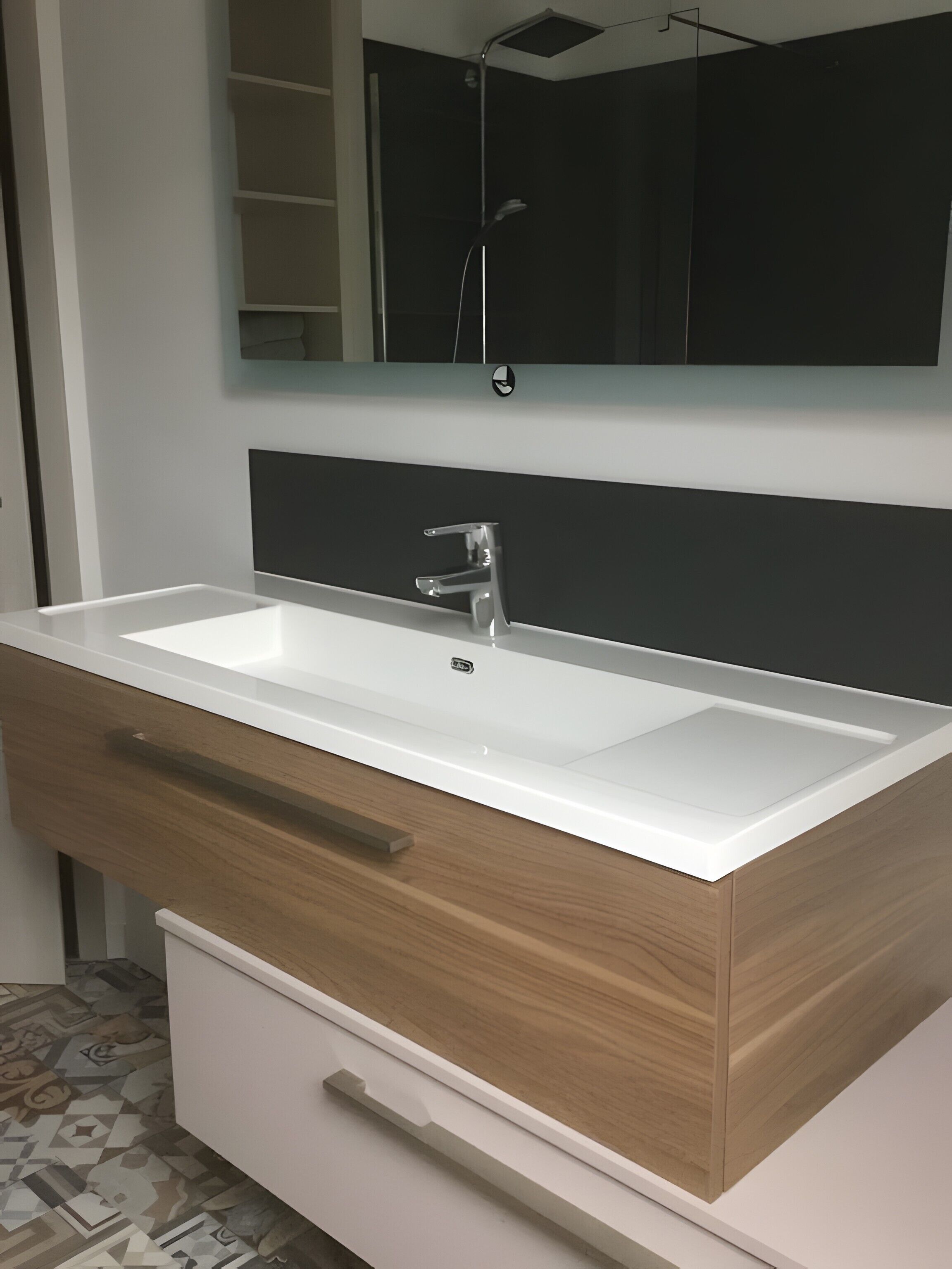 Un baño con un lavamanos blanco, un mueble de madera y un espejo encima.
