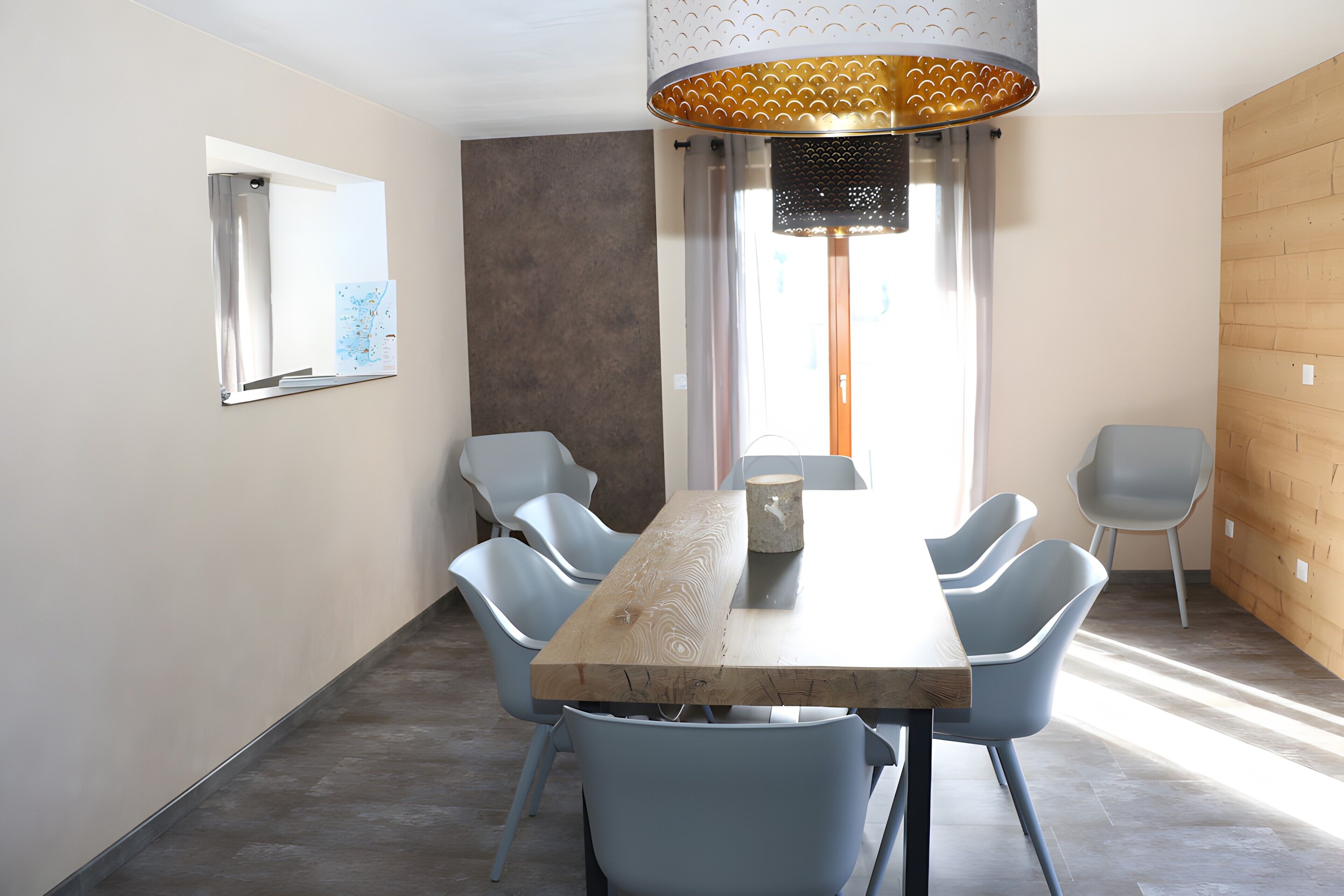Een eethoek met een houten tafel, zes stoelen, een hanglamp en een raam met gordijnen.