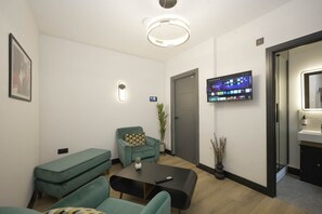 A modern living room with a sofa, a coffee table, a TV mounted on the wall, and a door leading to a bathroom. - The Sixty | Premier 1BDR Apartment | Cardiff City (Cardiff)