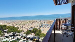 A balcony with a view of a beach, outdoor seating, and a clear sky. - Seaside escape for perfect vacations (Lignano Sabbiadoro)