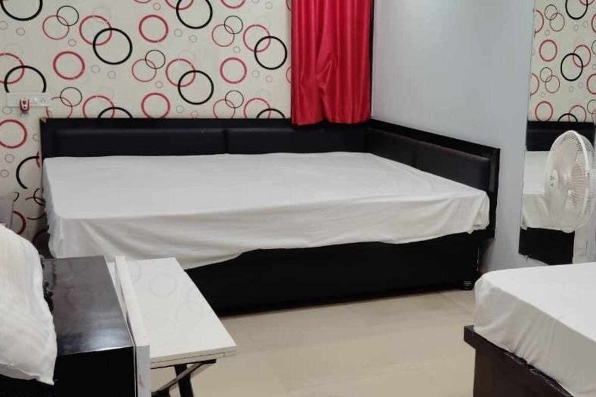 A room with two beds, a red curtain, and a wall with circular patterns.