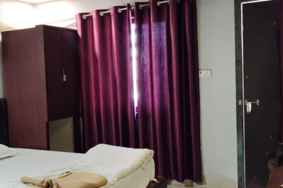 A hotel room with a bed, a wardrobe, and a door.