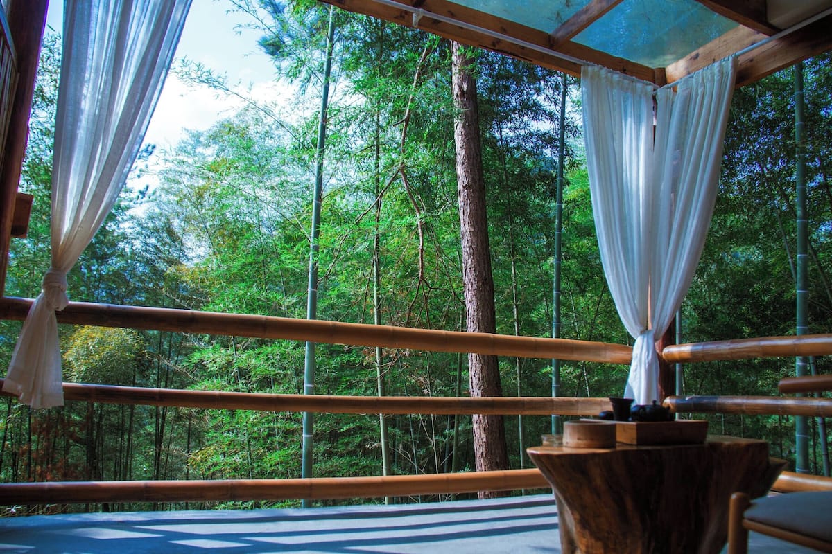 Una habitación con un ventanal grande, vigas de madera y vistas a un bosque.
