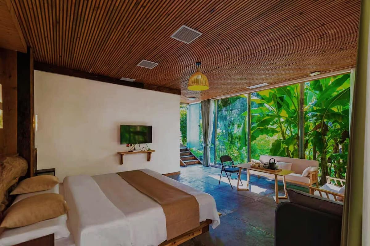 Un dormitorio con cama, televisor, mesa y sofá.