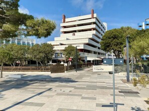 A multi-story building with a sign indicating 'Isola Strada' and 'Tungomare Trieste.' - Relaxing stay in a familiar flat (Lignano Sabbiadoro)