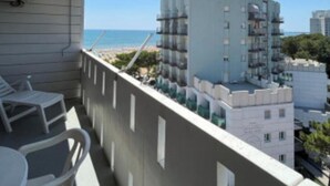 Un balcón con vista al mar y un edificio alto al fondo.