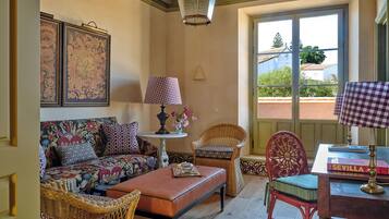 Una sala acogedora con un sofá, dos sillones de mimbre, una mesa con una lámpara y vistas a través de una ventana.