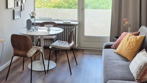 En stue med sofa, stole, spisebord og udsigt gennem et stort vindue.