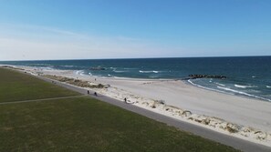 A coastal road with a beach, a grassy area, and the ocean.