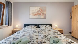 A double bed with floral bedding, two bedside lamps, a wooden wardrobe, and a painting on the wall. - Apartment “Linie 8” with Wi-Fi (Dresden)